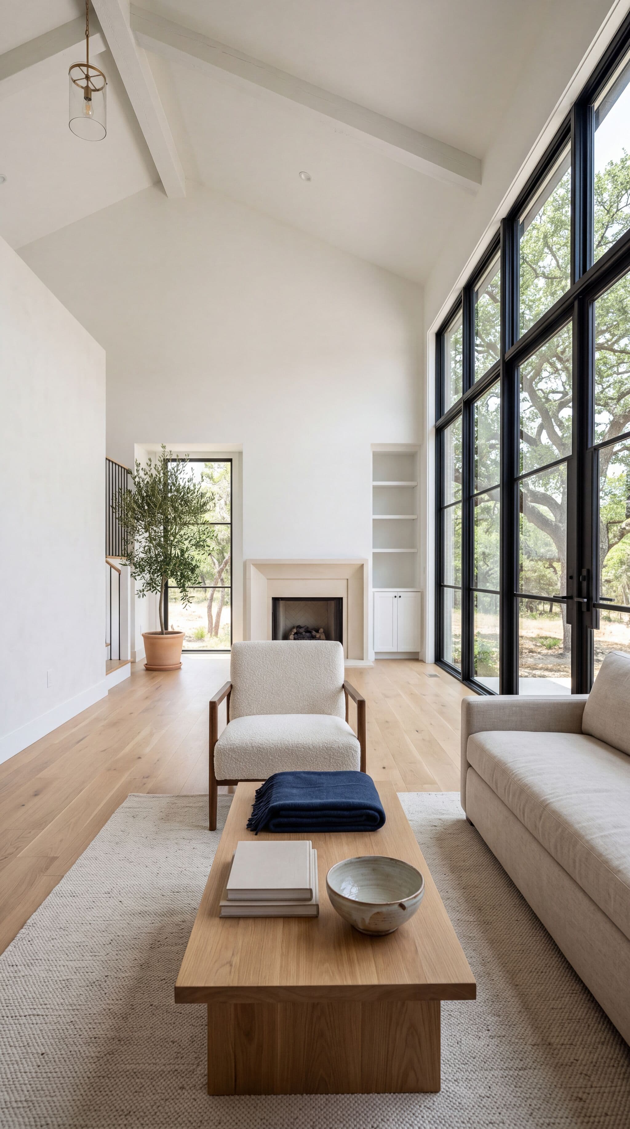 A bright, clean living room with tall windows looking out on live oak trees